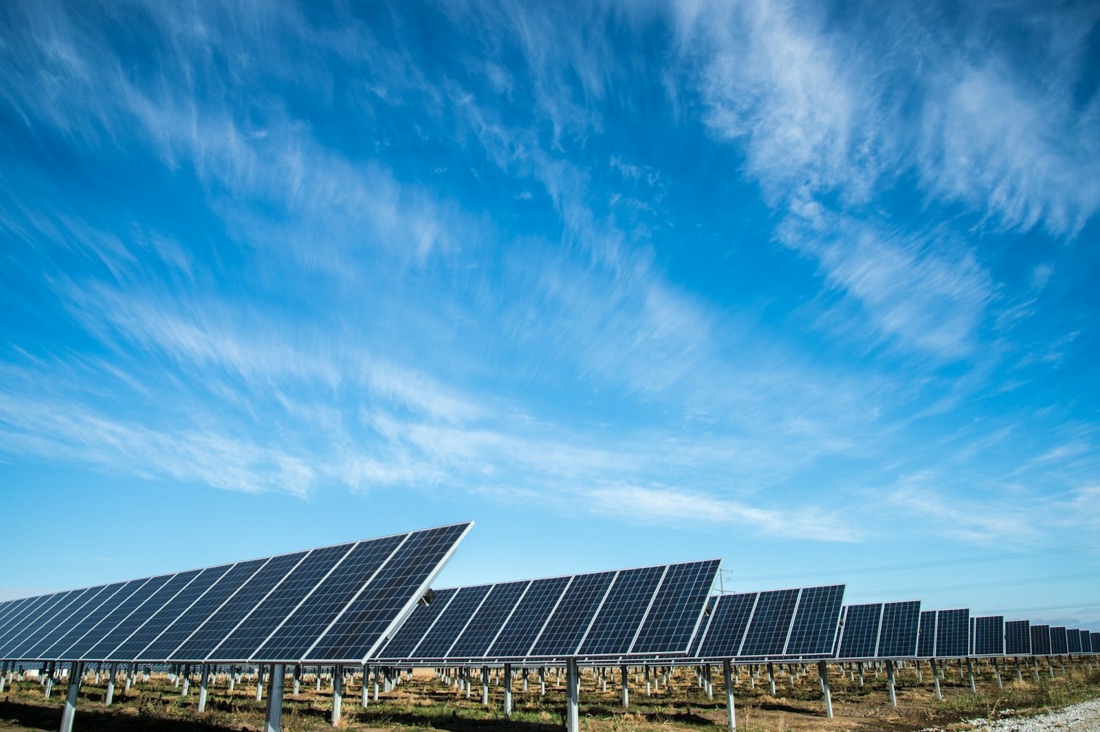 Rows of photovoltaic solar panels under a bright sky