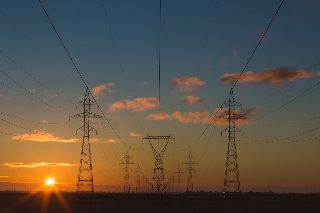 High-voltage transmission towers silhouetted against a sunset sky
