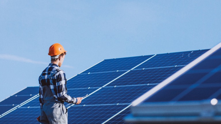 Installer in a hard hat securing a rooftop solar array